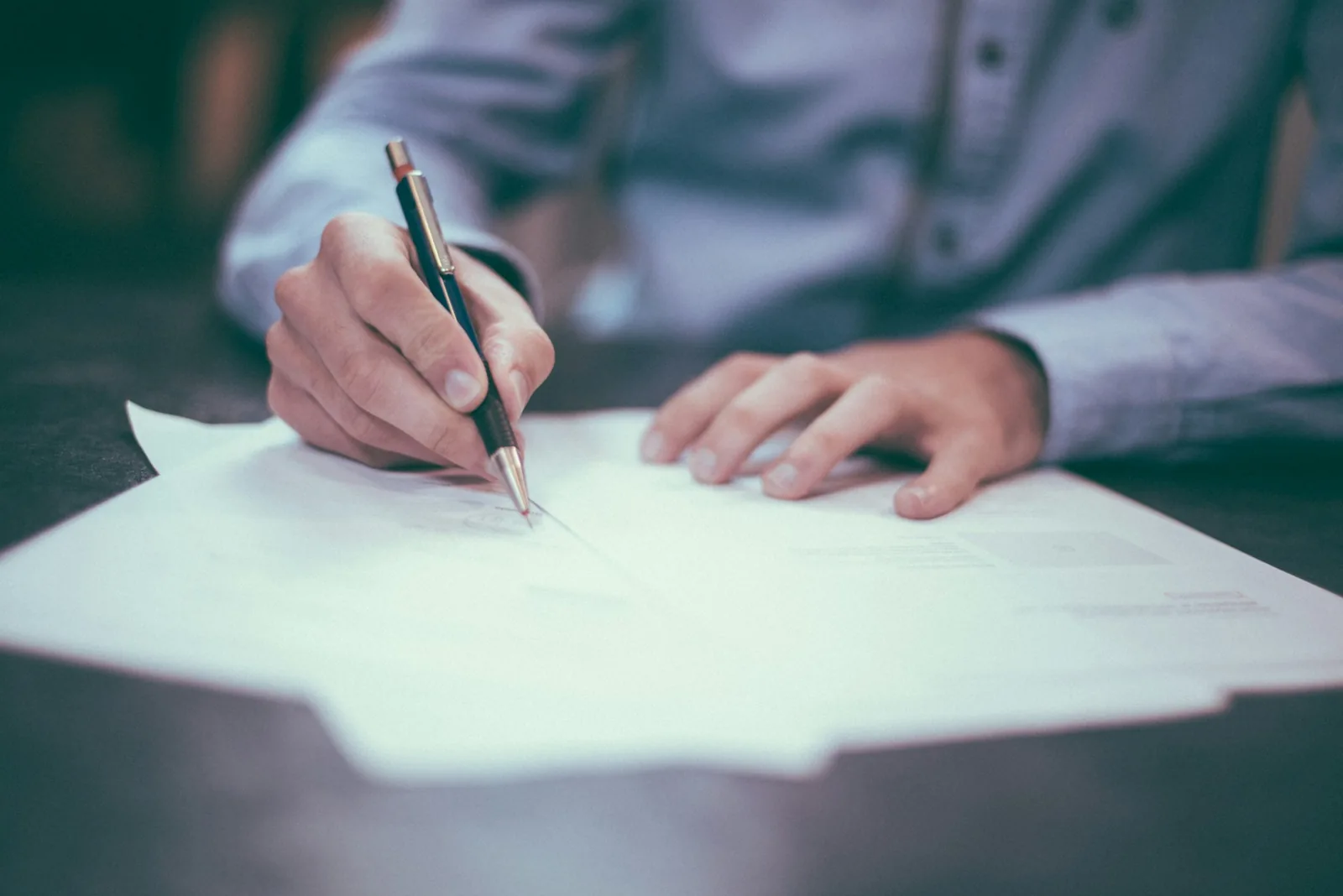 A person signing a document with a pen, representing the written mandate that appoints an authorised representative