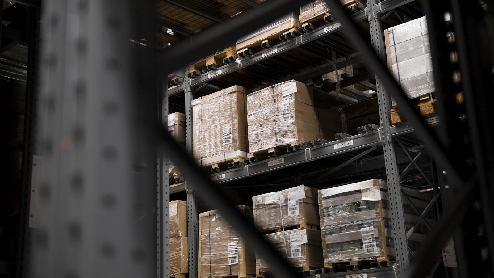 A fulfilment warehouse with pallets of boxes on racking, representing Amazon FBA storage