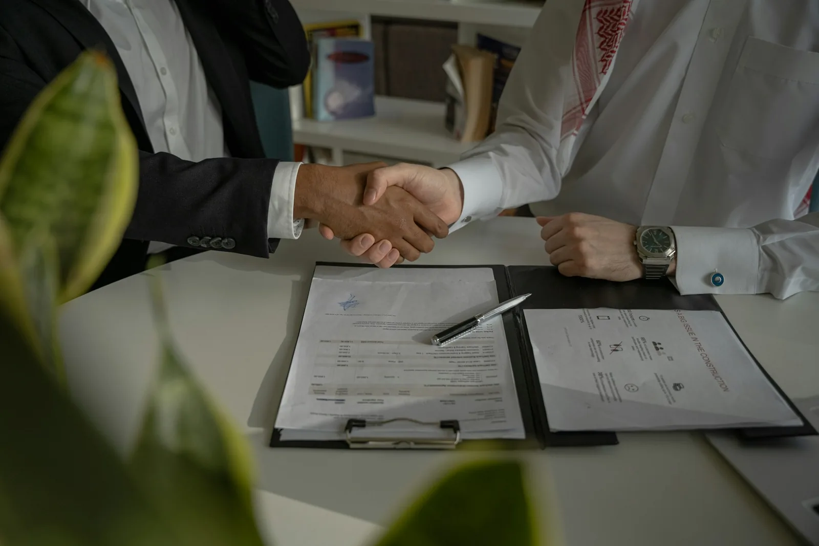 Two people shaking hands over a document, representing appointing an authorised representative