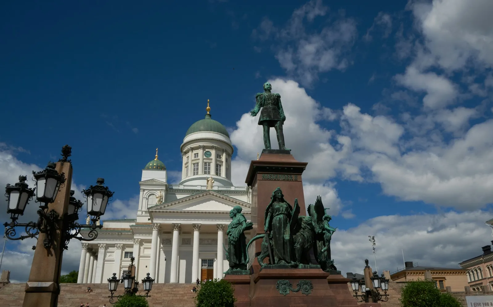 Helsinki Cathedral's white neoclassical facade and green dome rising behind the bronze statue of Alexander II in Senate Square