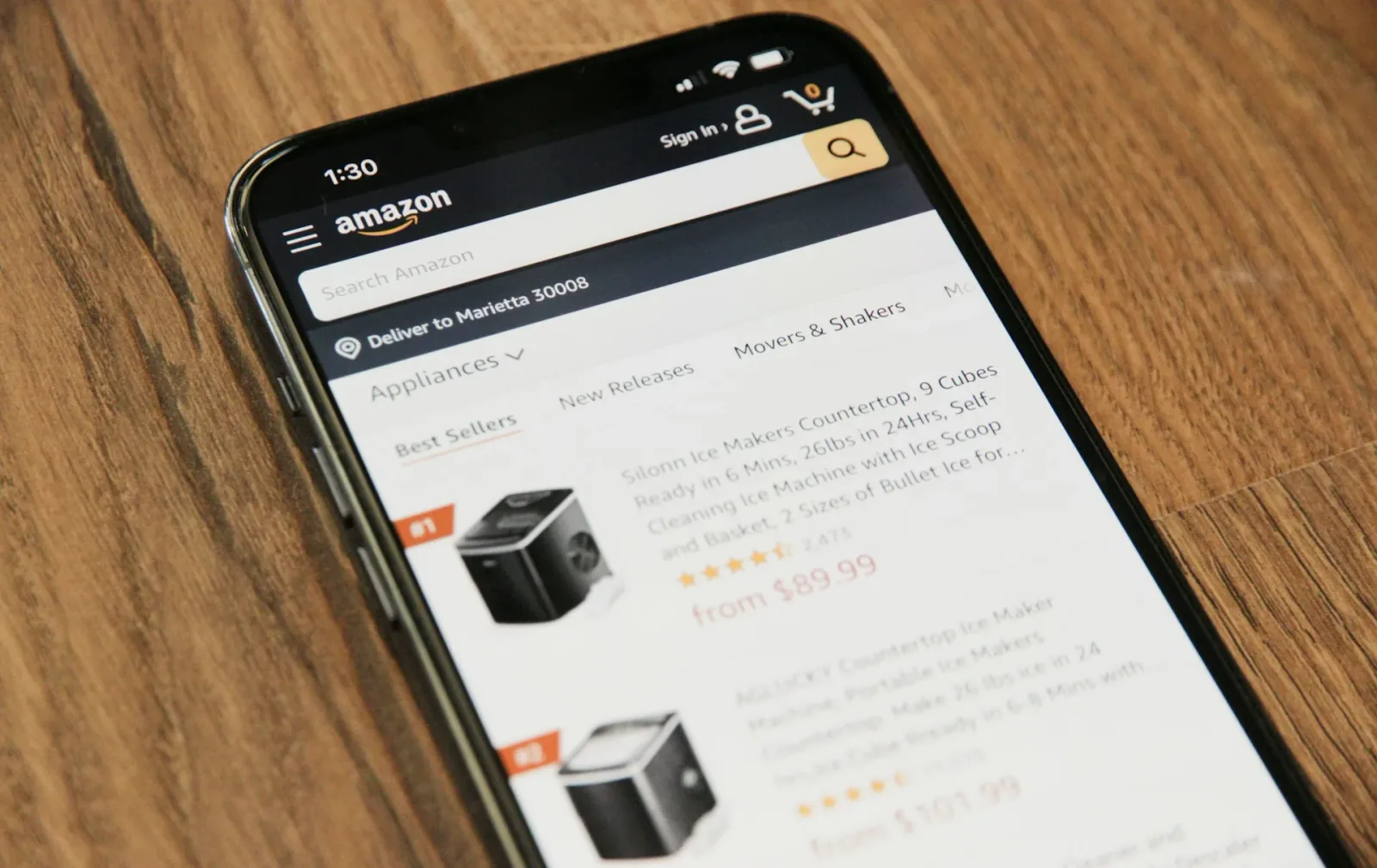 Smartphone on a desk showing the Amazon shopping app storefront