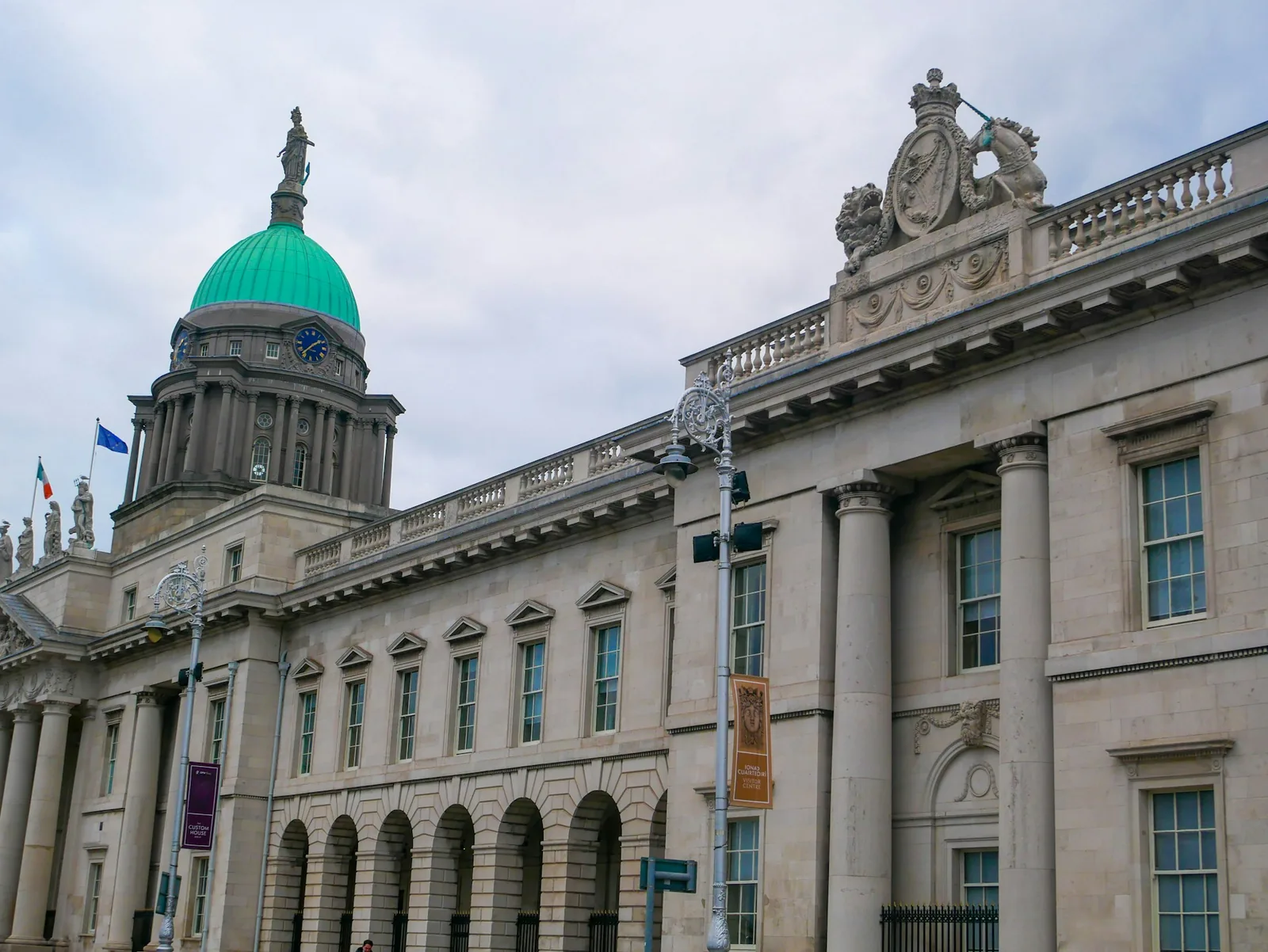 The Custom House in Dublin, its neoclassical stone facade topped by a green copper dome and statue, flying the Irish flag