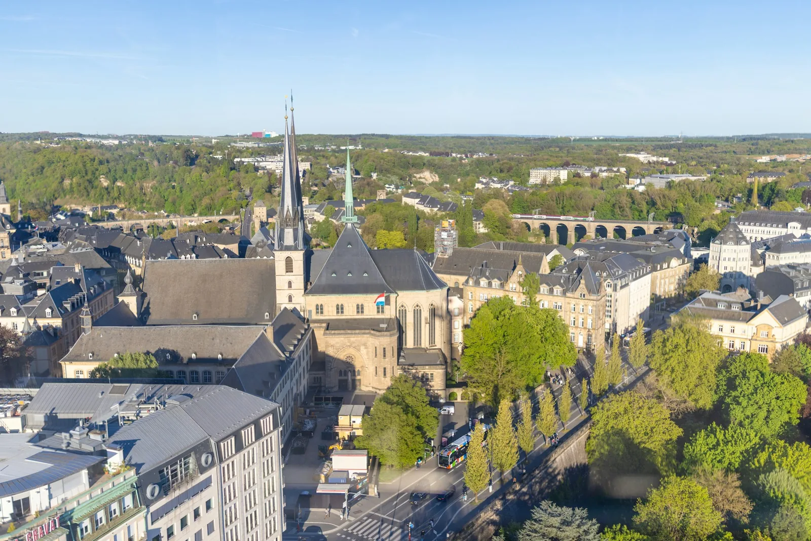 An aerial view of Luxembourg City's old town, the Gothic spire of Notre-Dame Cathedral flying the national flag above the rooftops