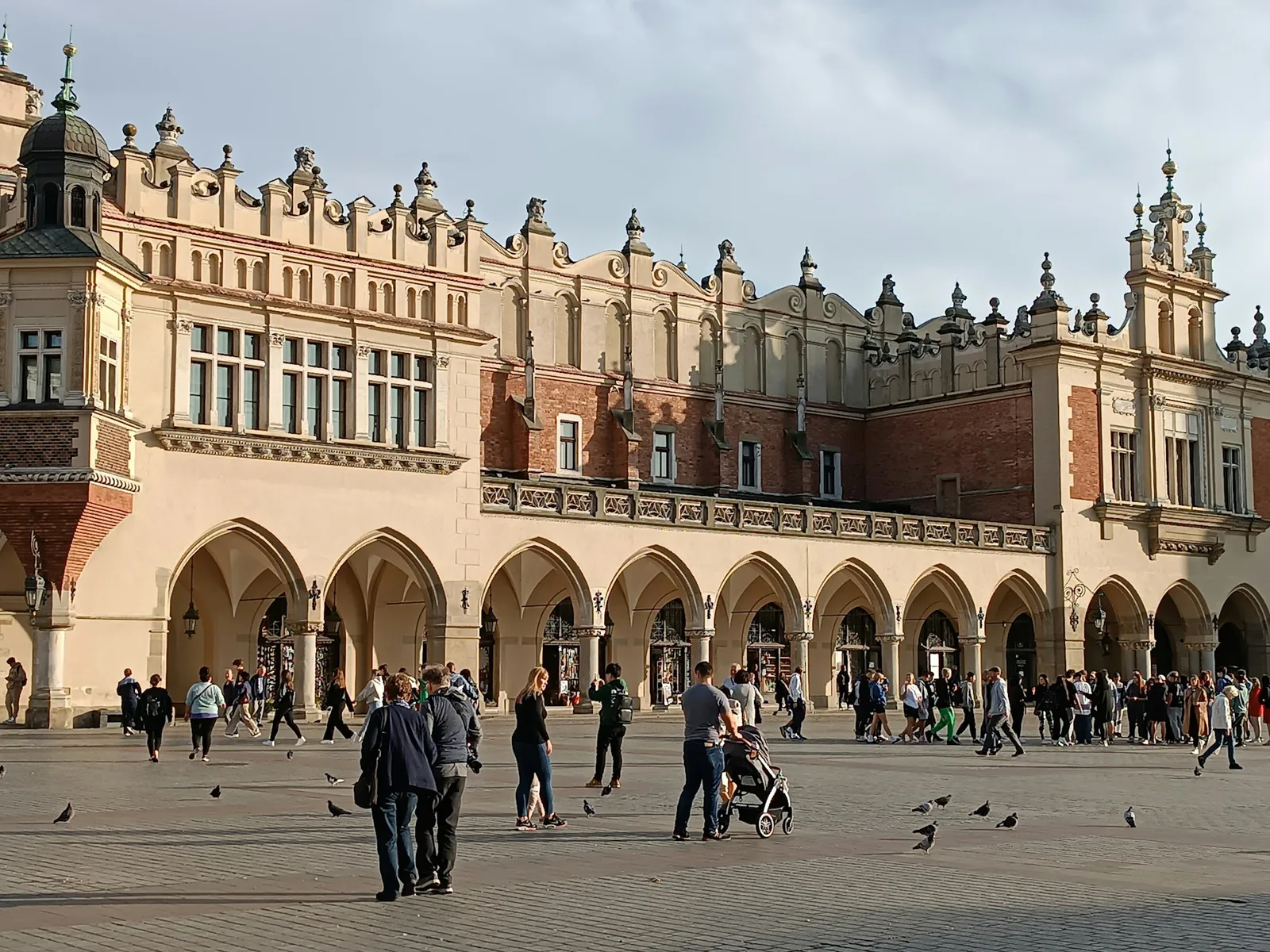 The Renaissance Cloth Hall (Sukiennice) in Krakow's main market square, its long arcaded trading gallery busy with people under a bright sky