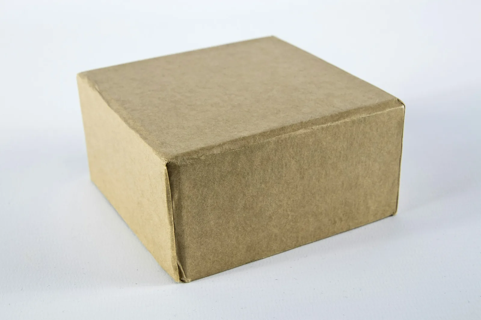 A plain brown cardboard shipping box on a white surface, the packaging unit whose specifications you collect