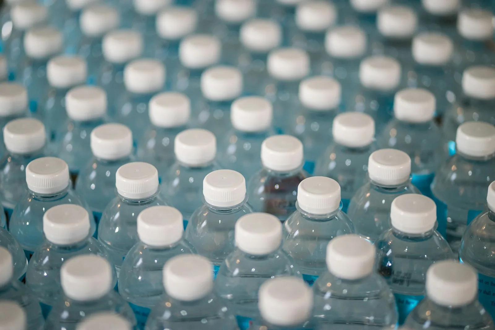 Rows of clear plastic water bottles with white caps