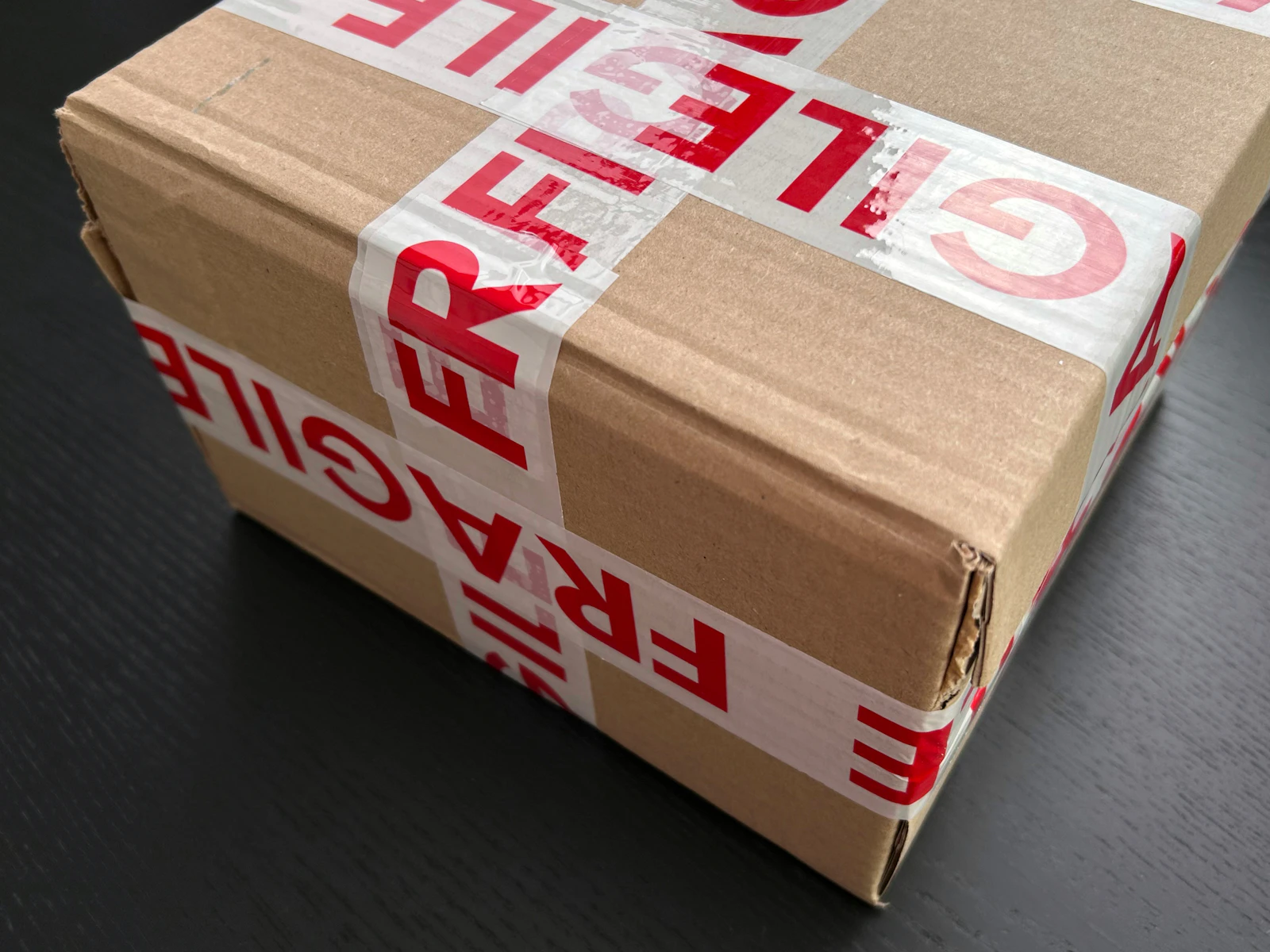 A cardboard parcel wrapped in red fragile tape, representing protective packaging for e-commerce